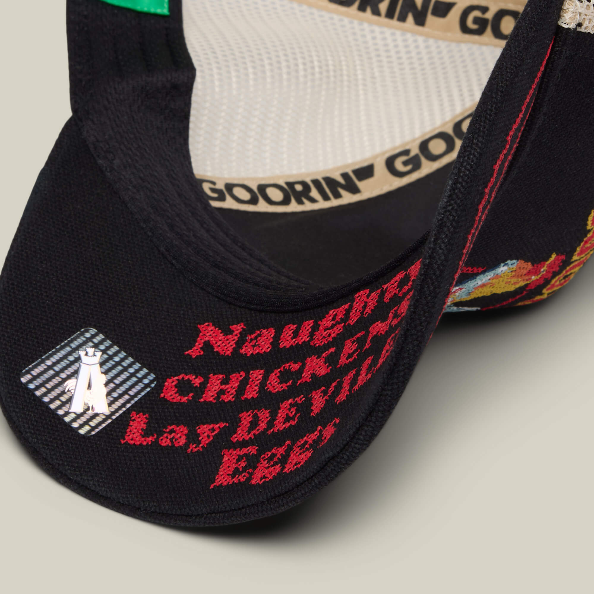 Close-up of the black Goorin Bros. "Middle of No Where" cap with embroidered text "Naughty CHICKENS Lay DEVILED Eggs," a small white animal patch, and colorful stitching—ideal for fans of home cookin’ or rustic charm.