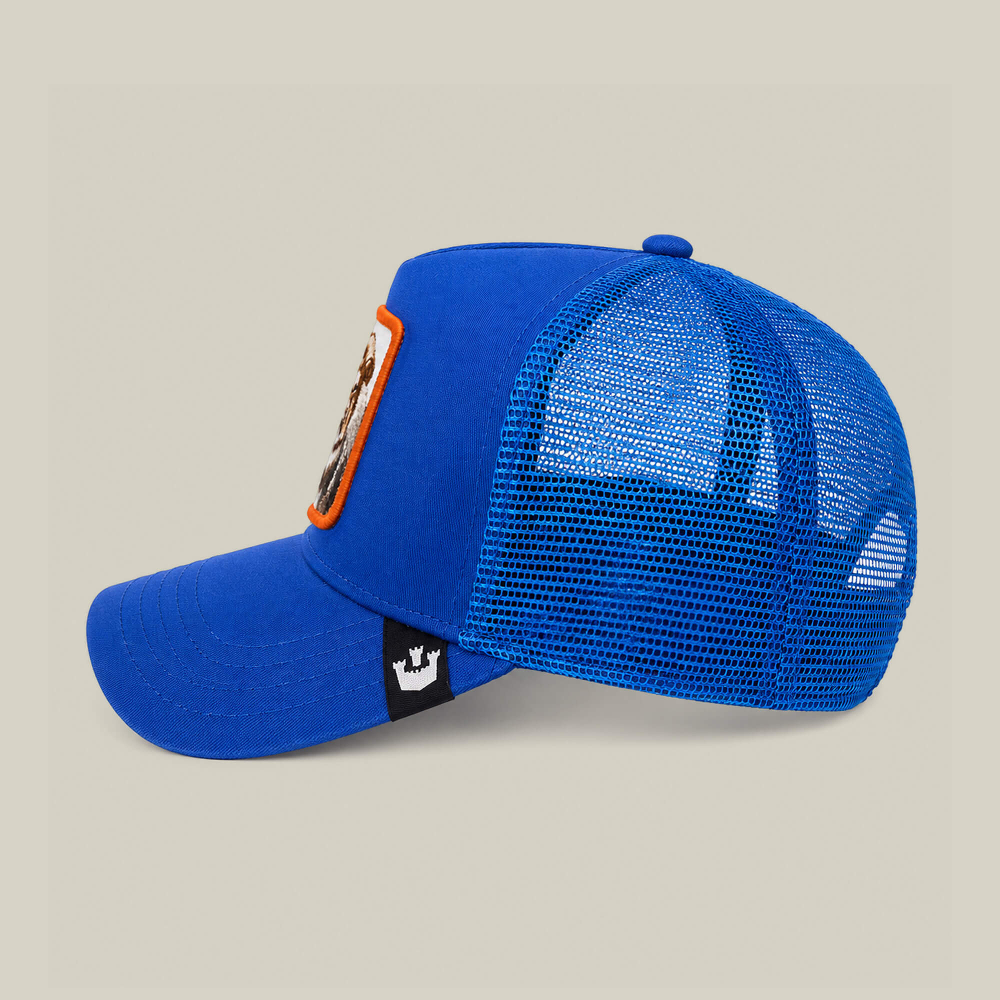 The Empire State of Mind by Goorin Bros. is a blue mesh trucker cap with a curved brim, front patch, and side black tag—shown in profile on a plain background. Pre-order this exclusive design now.