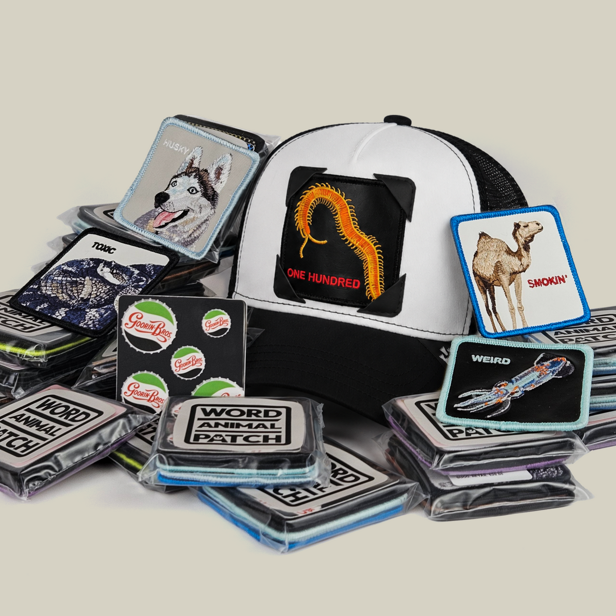 A Throwback Patch Pack with GB Patch Corner Trucker - Black and White featuring a centipede emblem, surrounded by various embroidered animal patches and a sticker sheet.