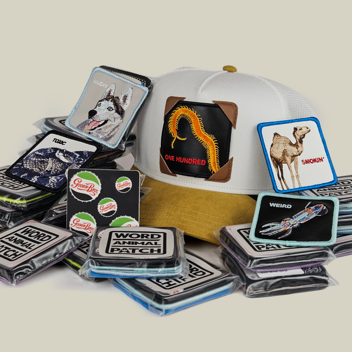 A Goorin Bros. Throwback Patch Pack with GB Patch Corner Trucker - Tan hat surrounded by various animal-themed patches in plastic packaging.