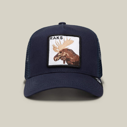 The Goorin Bros. Rakell Moose is a navy mesh trucker hat featuring a rectangular patch with an embroidered moose and "RAKS" above it, inspired by Rickard Rakell. This limited-edition cap is shown against a plain beige background.