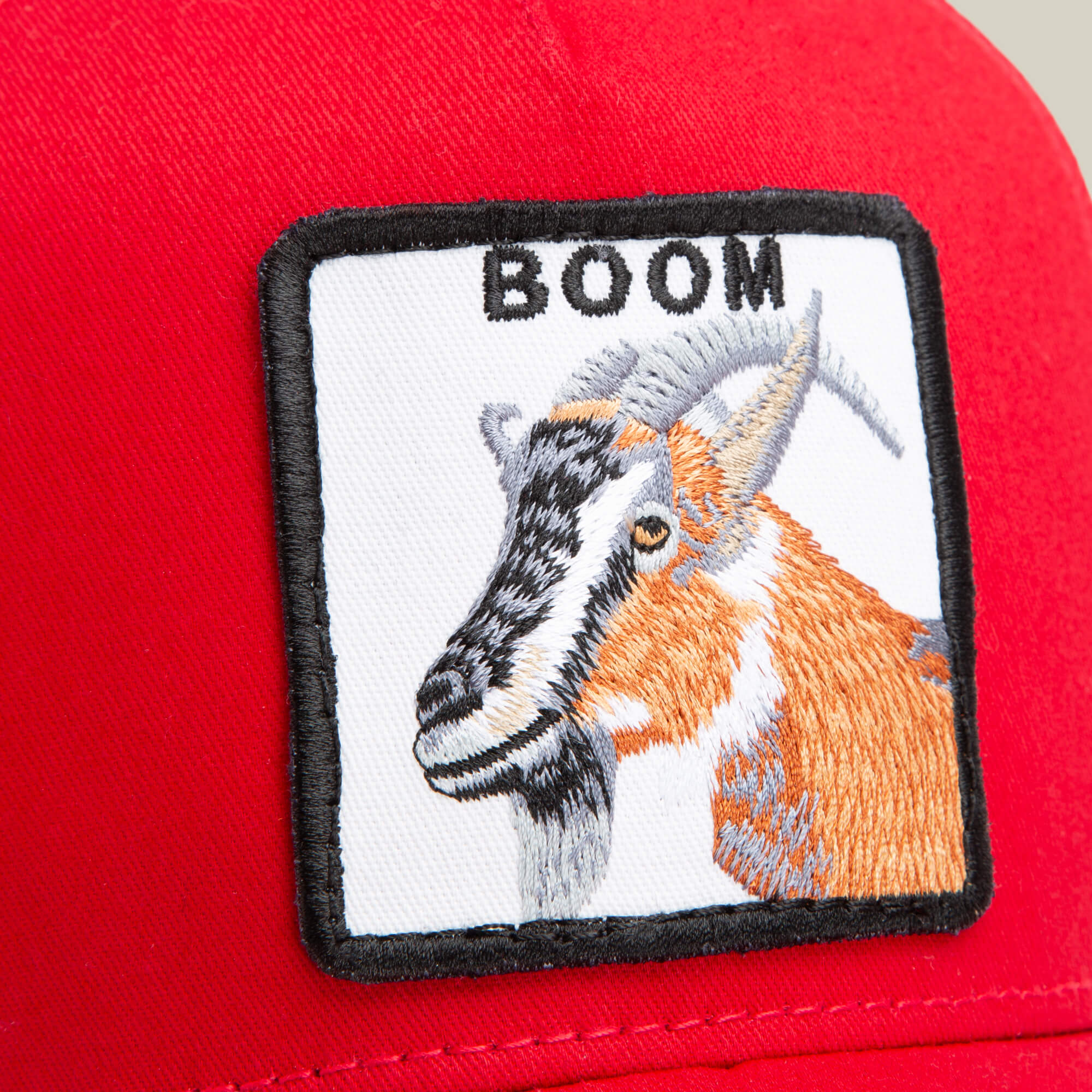 Close-up of the Dave Scott Boom Goat hat by Goorin Bros., showcasing a square patch with an embroidered goat and "BOOM" above it—the ideal accessory for any GOAT legend.