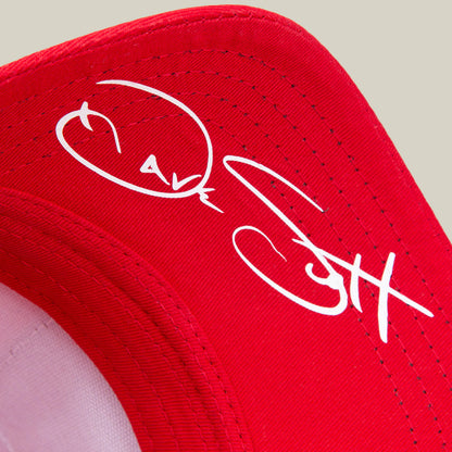 A close-up of the red Dave Scott Boom Goat hat by Goorin Bros., featuring a white autograph on the underside of the brim, as a tribute to a true GOAT legend.