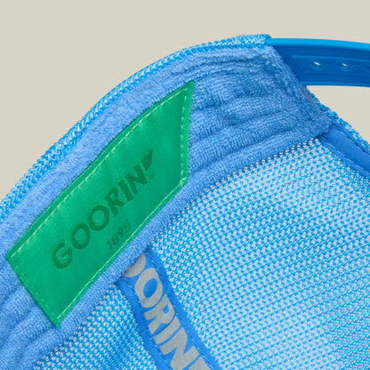 Close-up of the inside of a blue mesh cap by Goorin Bros., featuring a green label with the year 1895 printed on it, from their Squeaky Clean collection—looking as fresh as after bath time.