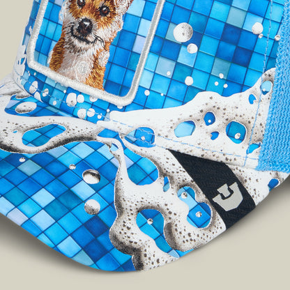 The Squeaky Clean cap by Goorin Bros. features a blue and white tile pattern inspired by bath time, playful cartoon water splashes, and an embroidered patch of a small dog on the front.