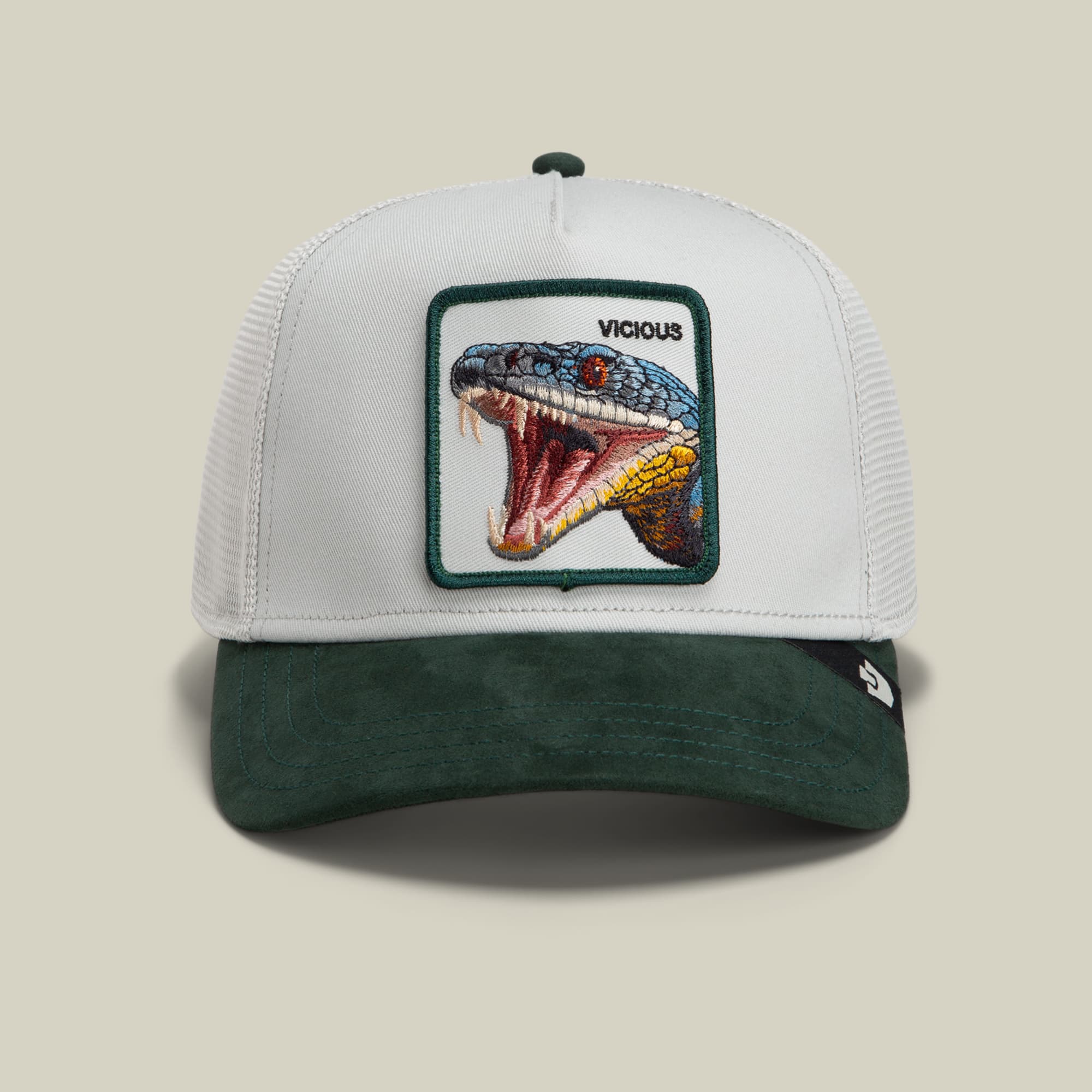 The Goorin Bros. Suede Snake trucker hat features a white mesh back and green suede front with an embroidered patch of a vicious snake with its mouth open, displayed on a neutral background.