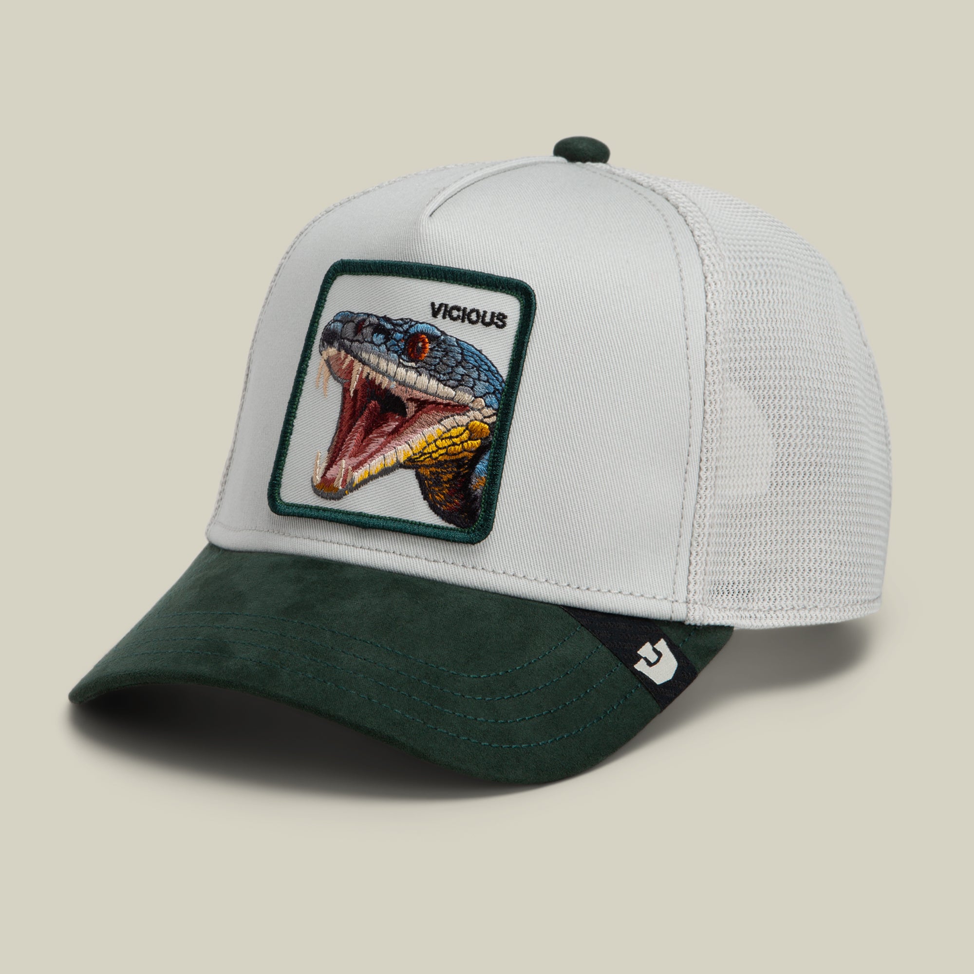 The Goorin Bros. Suede Snake trucker hat features a bold snake patch with an open-mouthed serpent and the word “VICIOUS” embroidered above it, all on a white and dark green cap with a mesh back.