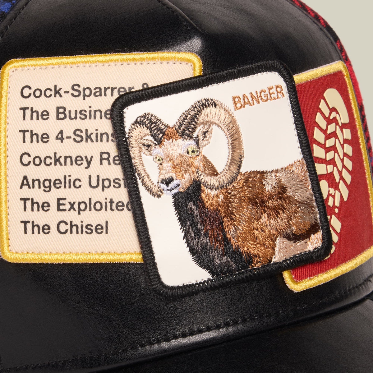 Goorin Bros. Banger trucker hat featuring an embroidered goat patch on black mesh with red and gold trim, displayed flat with visible text patches listing animal names.