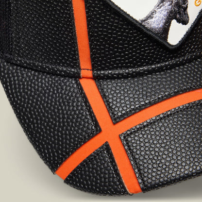 The Know Ball by Goorin Bros is a black basketball-inspired hat with orange fabric panels and mesh detailing, shown in a close-up product shot highlighting its breathable construction and athletic design.