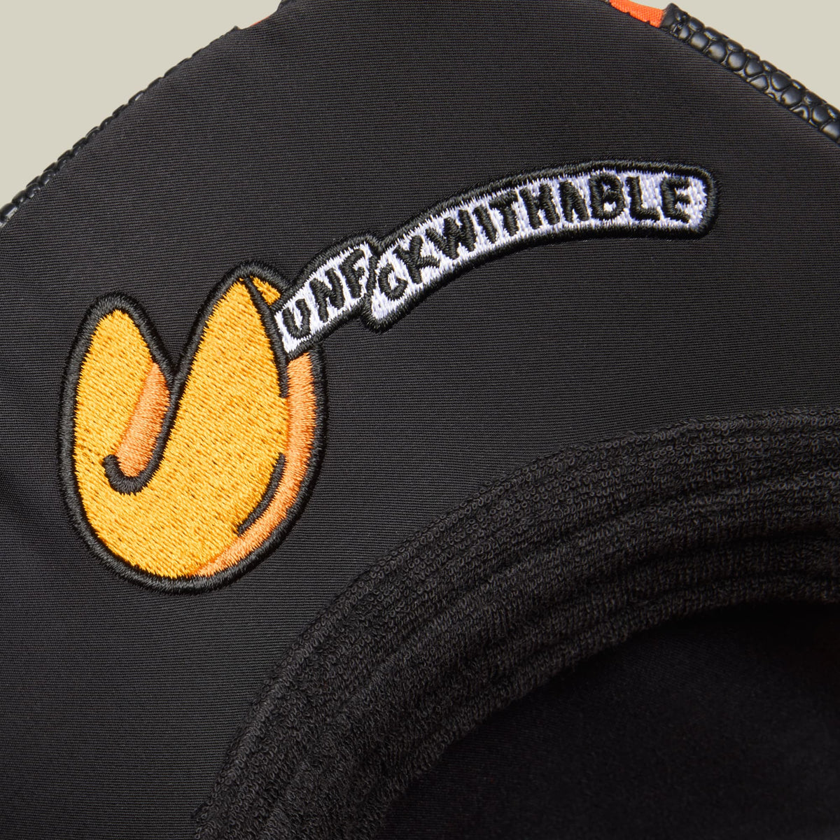 The Goorin Bros. Know Ball trucker hat features a black fabric crown with a yellow embroidered smiley face logo and white curved text on the front, shown in a close-up studio product shot.