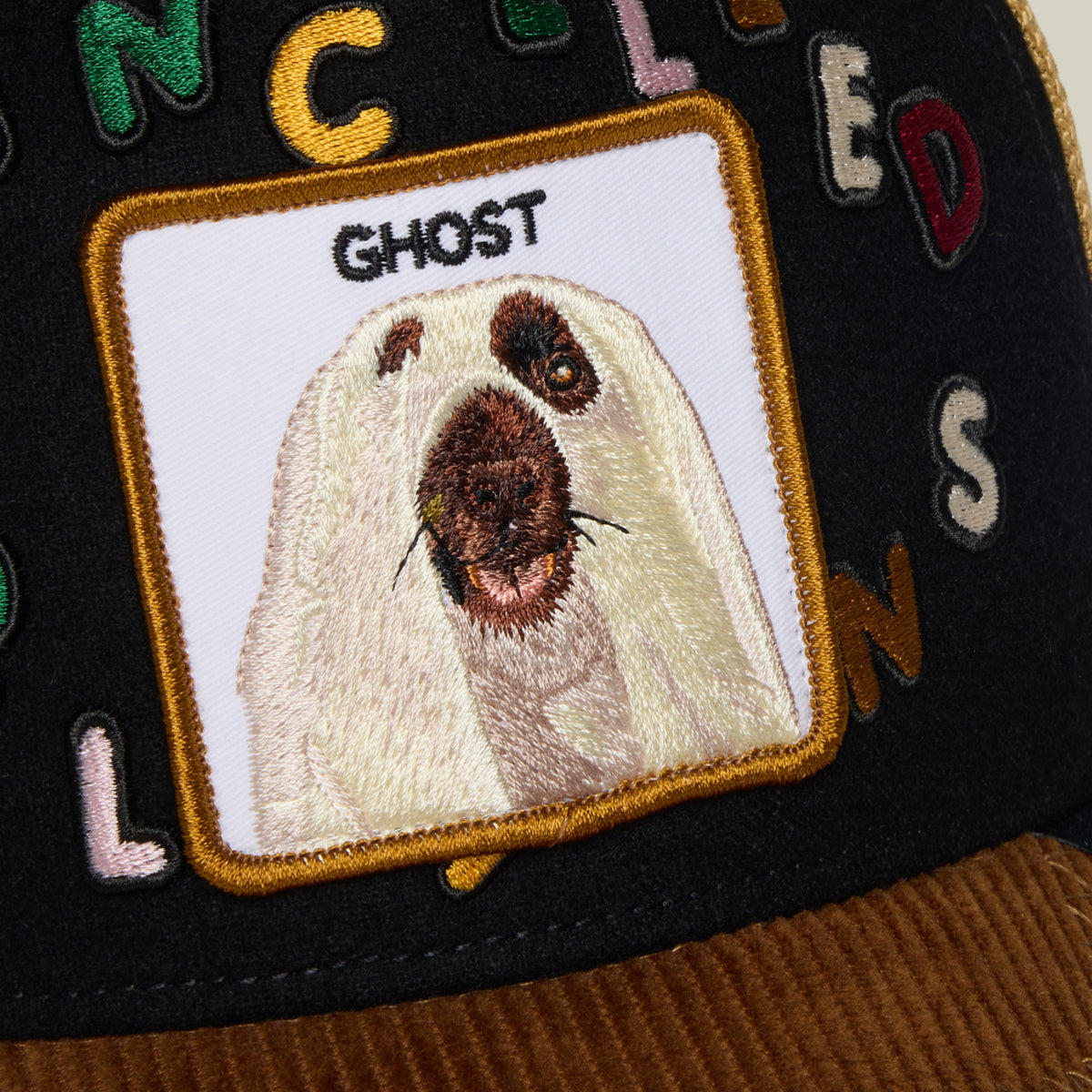 Way of the Samurai black cap featuring an embroidered patch of a long-haired dog with a dark muzzle above the word GHOST surrounded by colorful fabric letters.