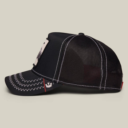 Down Low... trucker cap by Goorin Bros., featuring black mesh, white zigzag stitching on the bill, a rectangular badge of honor patch on the front, and white stitching detail along the seams, displayed on a light background.
