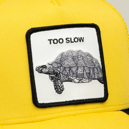 Close-up of the Goorin Bros. “Down Low...” yellow cap, featuring a rectangular patch with an embroidered tortoise and the words TOO SLOW above it—a true badge of honor for those lucky enough to snag this elusive drop.
