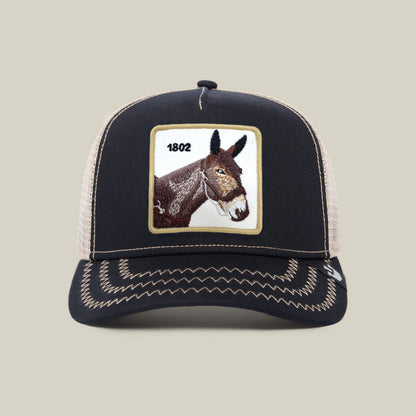 The Goorin Bros. 1802 Mule trucker hat features a black front with an embroidered mule’s head and “1802,” plus a beige mesh back.
