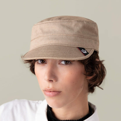 A person with short brown hair wears the Goorin Bros. "Home at Last" beige hat and a white collared shirt, facing forward against a plain light background.
