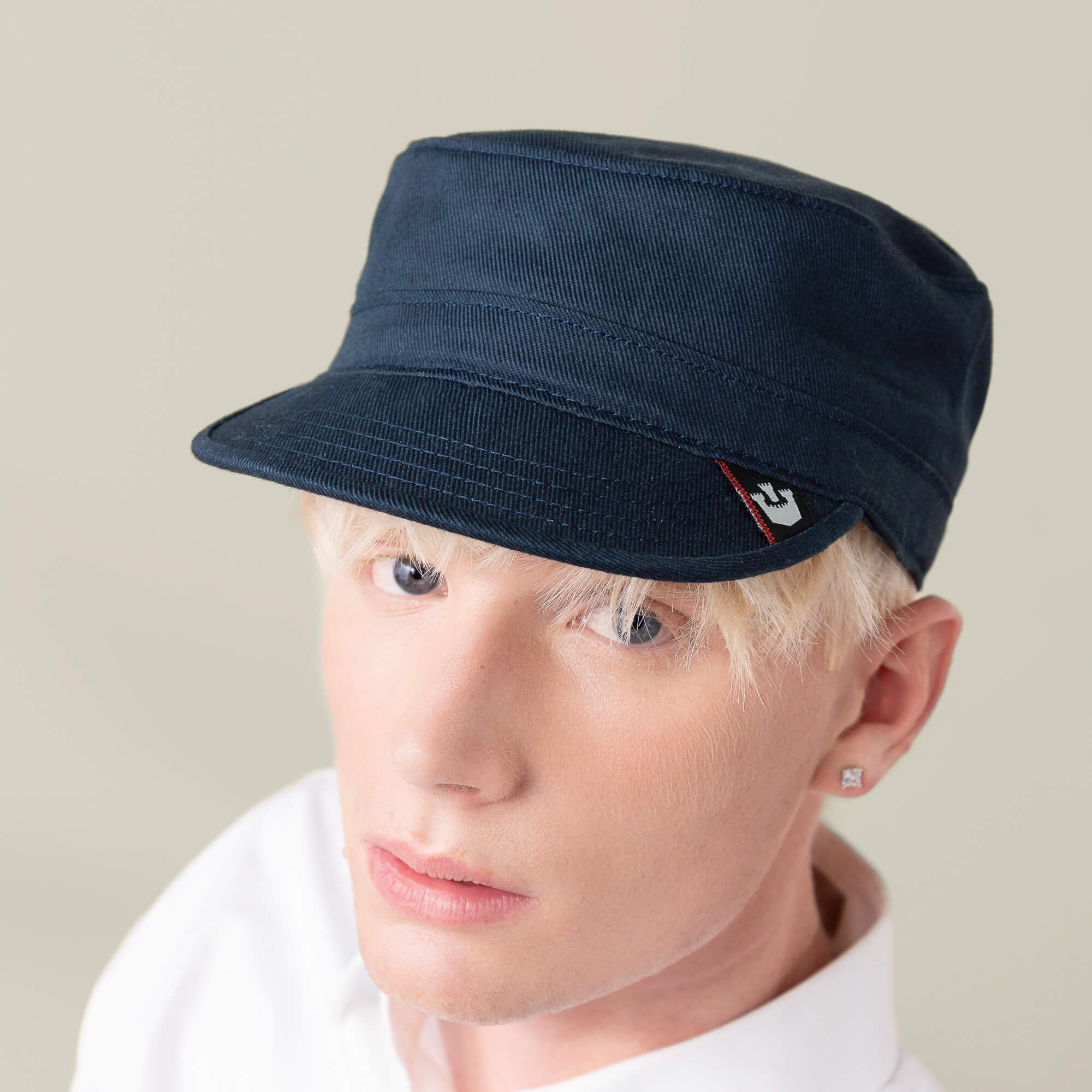 A person with light blond hair wears the Goorin Bros. "Home at Last" navy blue hat and a white shirt, facing the camera with a neutral expression.