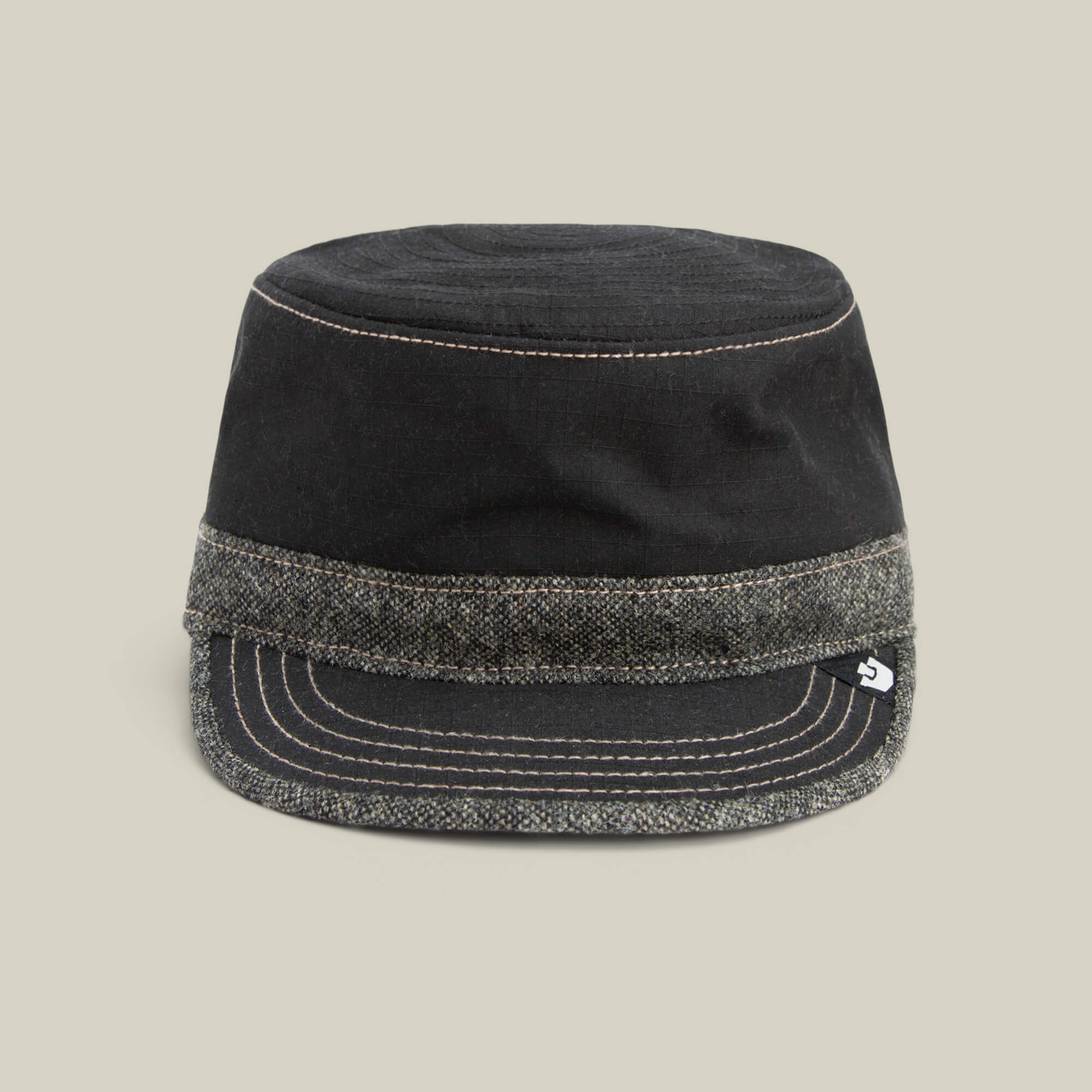 The Goorin Bros. Ampere cap in VOID features a flat top, short brim, and a grey tweed band at the base, shown against a plain beige background.