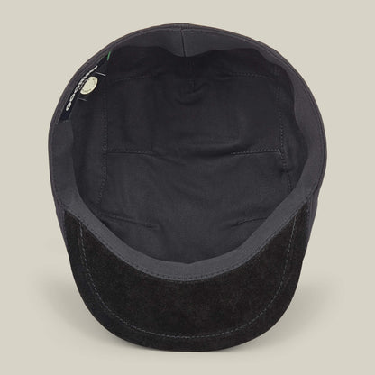 The Goorin Bros. Heatherwood is a black cotton suede flatcap, shown from above to highlight the inside lining and a small tag near the edge, emphasizing its quality craftsmanship as it is handmade in the USA.