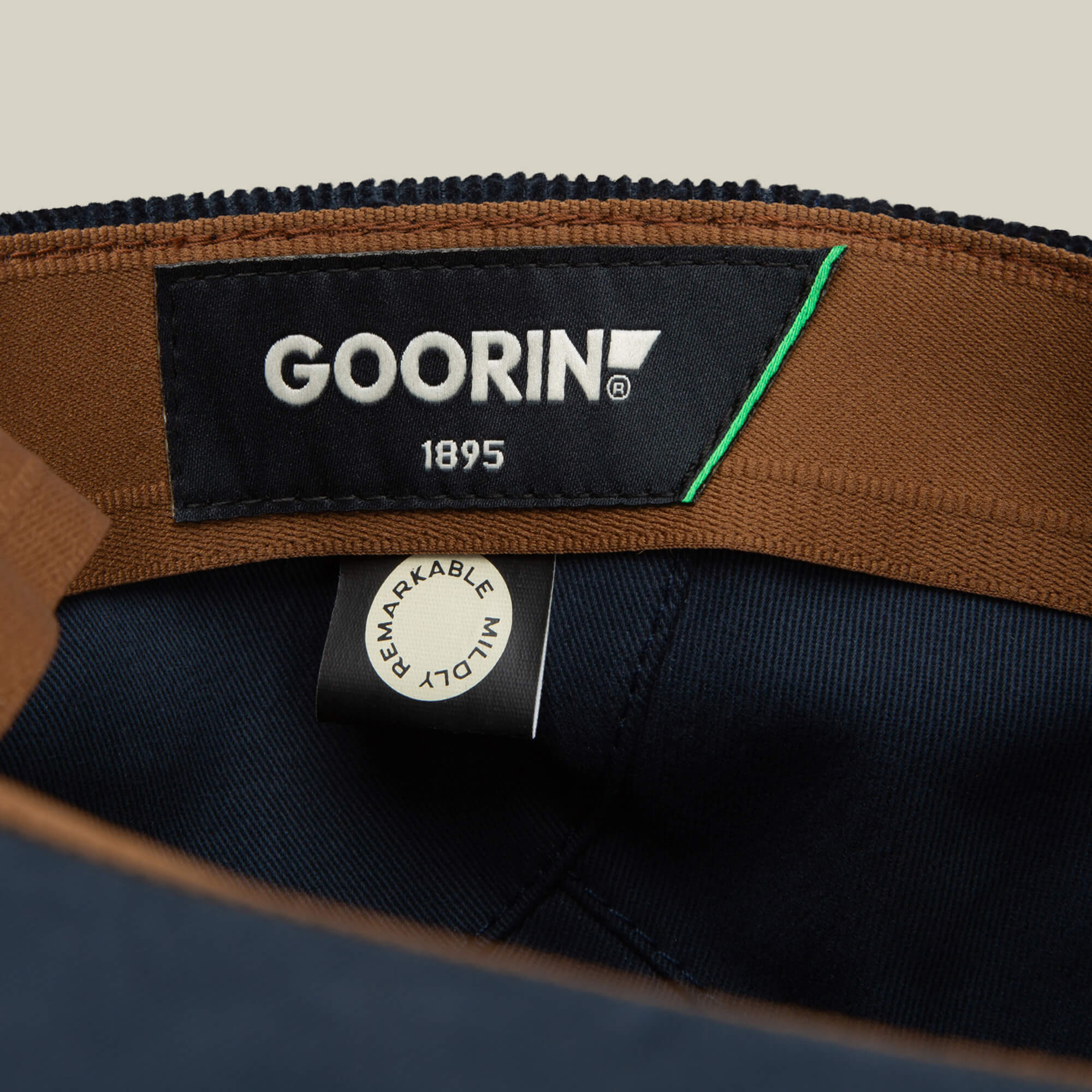 Close-up of a Cozy Low Profile interior by Goorin Bros., featuring a black GOORIN 1895 label and a white REMARKABLY MADE tag stitched to brown and navy blue fabric—an ideal everyday flatcap detail.