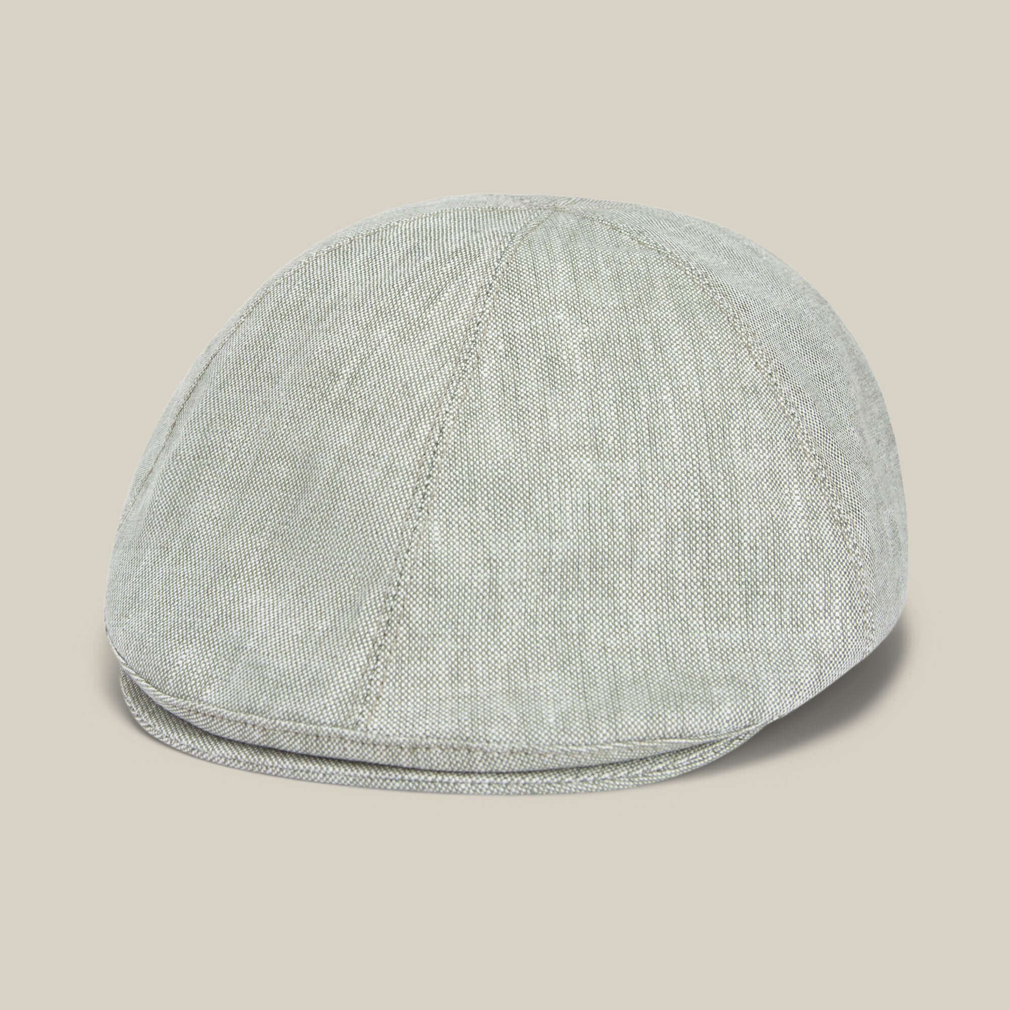 The Benjamin Paul flat cap by Goorin Bros. features light gray textured linen with visible stitching, making it a stylish everyday hat, displayed against a neutral beige background.