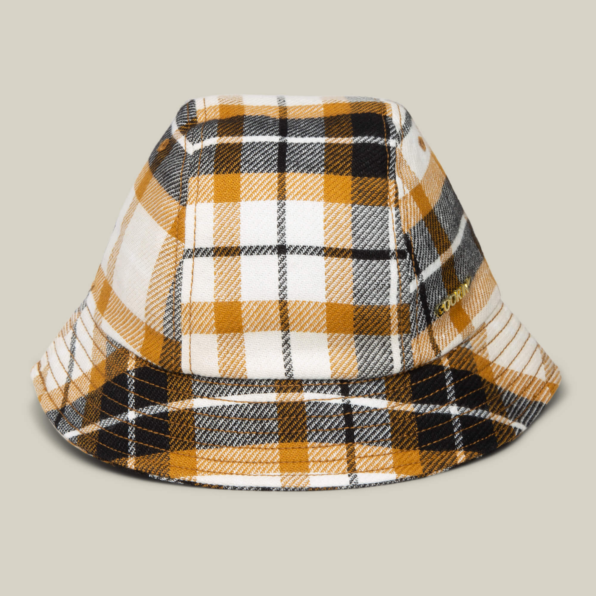 The Goorin Bros. Bespoke Wordmark Bucket hat in AMBER features a plaid pattern in yellow, black, and white, displayed against a plain beige background.