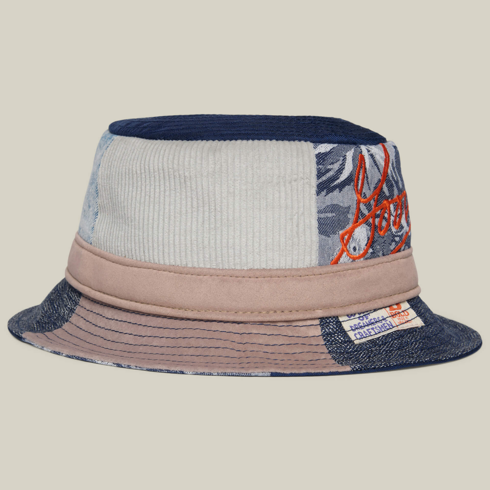 The Goorin Rework Bucket by Goorin Bros. is a USA-made bucket hat with mixed fabrics, a wide brim, orange embroidered text, and a sewn label on the brim.