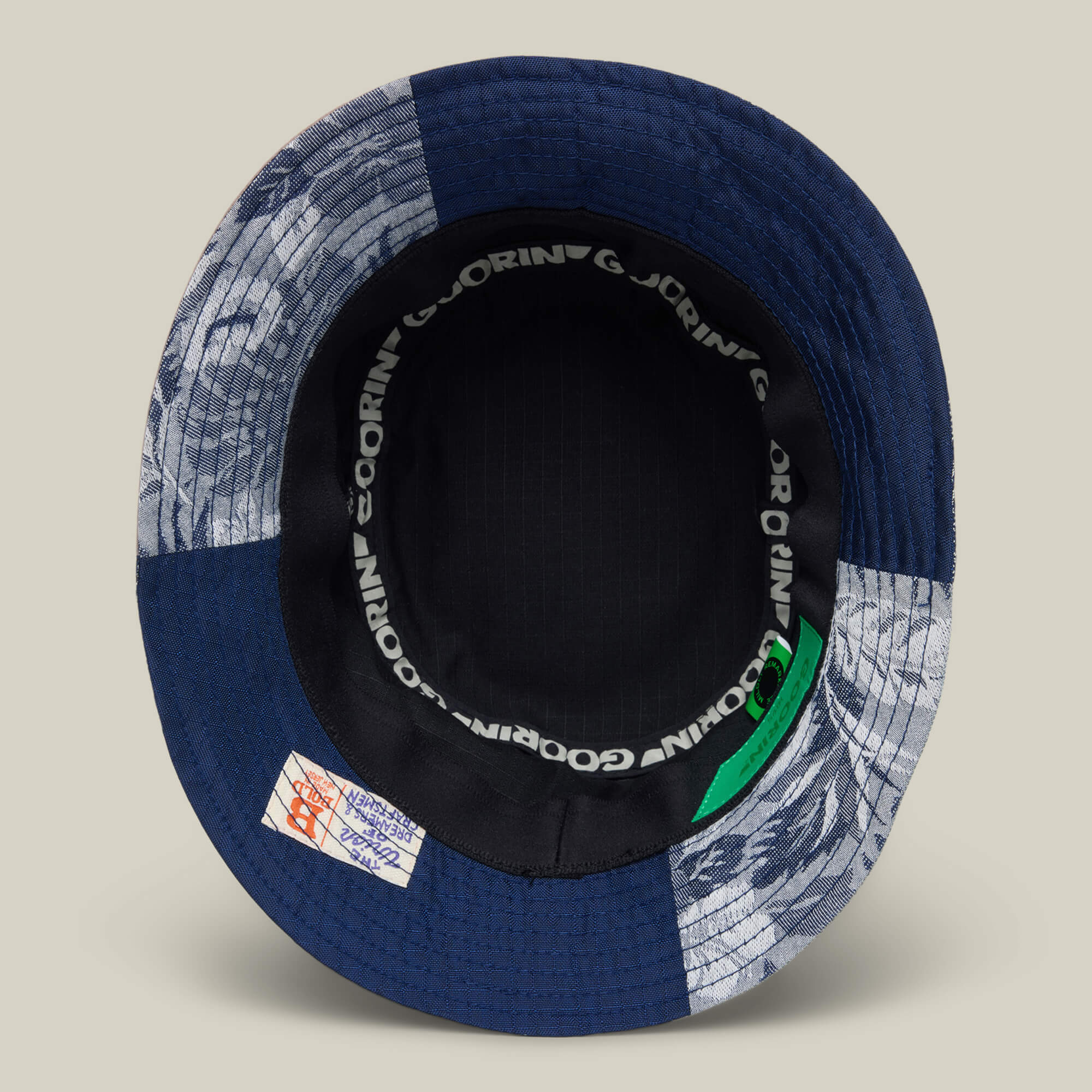 The Goorin Rework Bucket by Goorin Bros. is a patchwork bucket hat made from recycled blue and patterned fabrics, featuring a black inner band with repeated GORIN text and a stitched interior label.