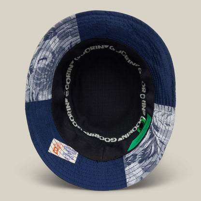 The Goorin Rework Bucket by Goorin Bros. is a patchwork bucket hat made from recycled blue and patterned fabrics, featuring a black inner band with repeated GORIN text and a stitched interior label.