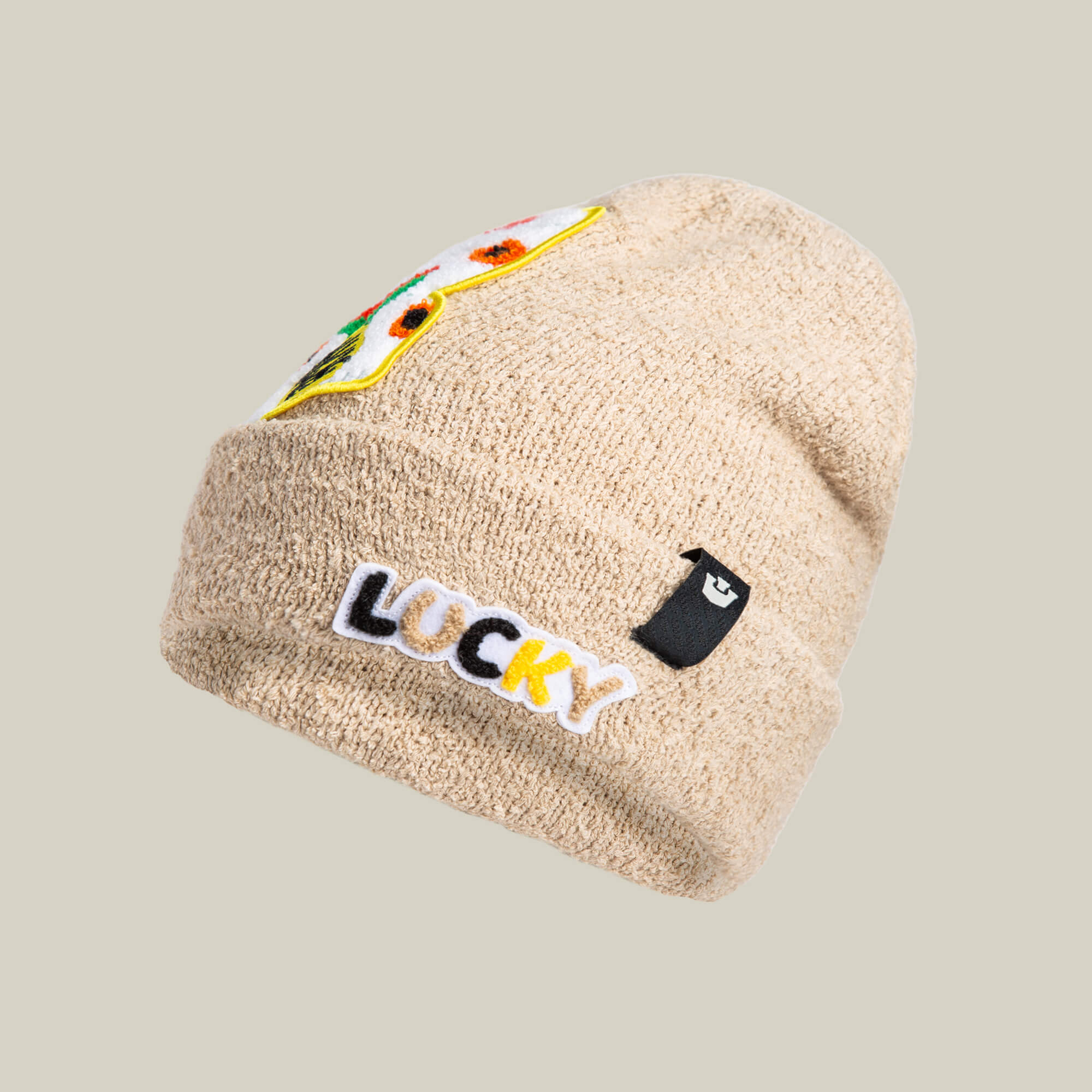 The Goorin Bros. Good Fortune beanie in PUFF features a warm knit design with an embroidered black and yellow LUCKY patch, a small black tag, and a colorful side patch for cozy lucky cat vibes.