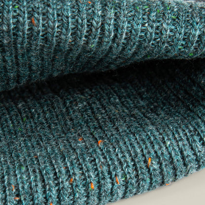 Close-up of the No Comply ribbed knit fabric by Goorin Bros., featuring teal yarn with flecks of orange and green—perfect for a warm, comfortable beanie.
