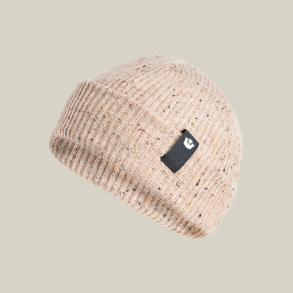 The Goorin Bros. No Comply beanie is a warm beige knit with a folded brim and a black patch featuring a white logo, set against a plain light background—ideal for cozy, stylish comfort.