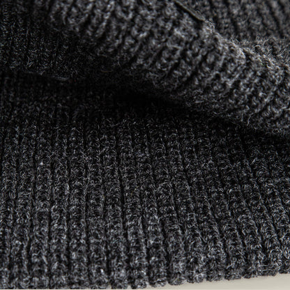 Close-up of a folded, dark gray, ribbed knit fabric highlights the texture—ideal for The Cancelled Beanie by Goorin Bros., making it a perfect choice for a charcoal knit cuff or a stylish skull patch accessory.