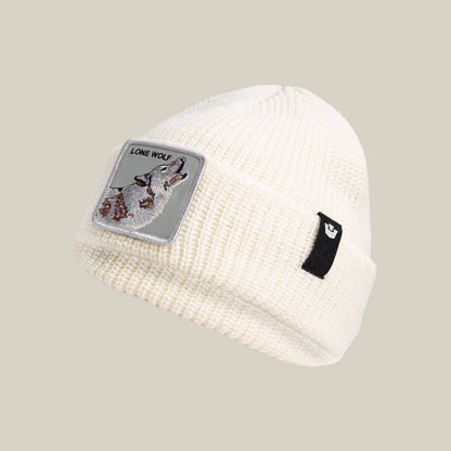 The Lone Wolf Beanie by Goorin Bros. is a white knit winter hat featuring a howling wolf patch labeled "LONE WOLF" and a small black tag on the cuff.