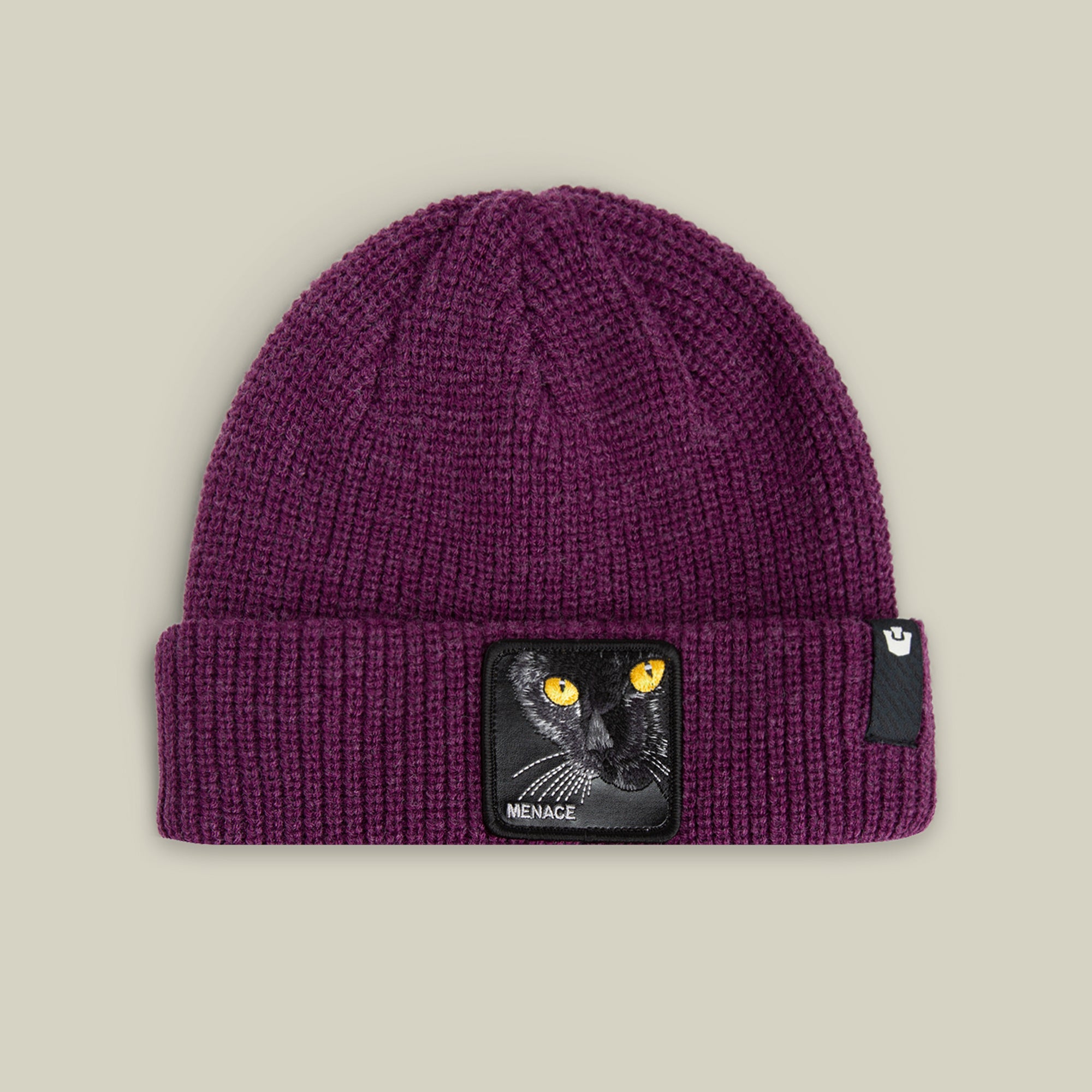 The Menace Beanie by Goorin Bros. in DESIRE features a black panther face patch with yellow eyes on the front fold, plus a small black tag.