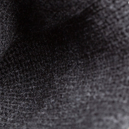 Close-up view of The Misfit Beanie by Goorin Bros., featuring black knit fabric with detailed weave patterns and a subtle cat patch adorned with striking red eyes.