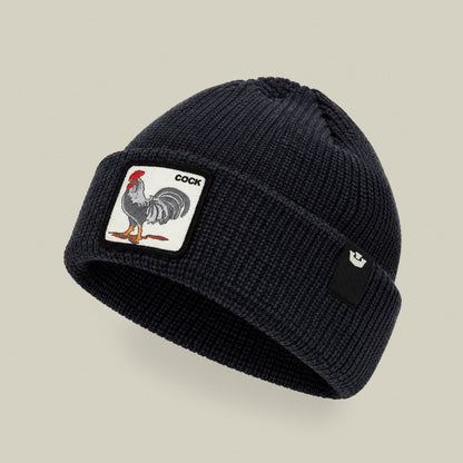 The Rooster Beanie by Goorin Bros is a black ribbed knit beanie featuring a rooster patch emblem on the front, displayed against a neutral beige background.