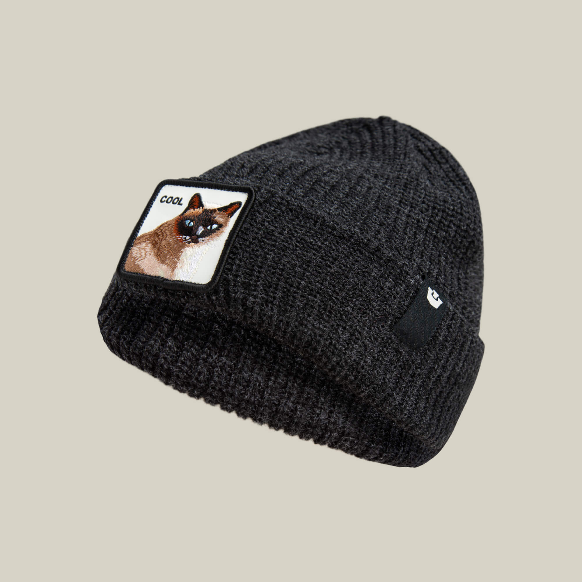 The Cool Beanie by Goorin Bros. is a dark black ribbed knit beanie featuring a patch with a cat and "COOL"—ideal for streetwear style. Shown on a plain, light background.