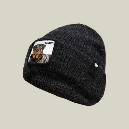 The Guard Beanie by Goorin Bros. is a black knit winter hat with a Rottweiler patch labeled "GUARD" on the front and a subtle black logo tag on the side—ideal for making a statement in cold weather.