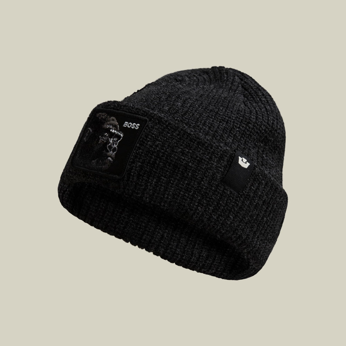 The Boss Beanie by Goorin Bros is a black ribbed knit beanie featuring an embroidered animal patch on the front and a small logo patch on the side, displayed against a neutral background.