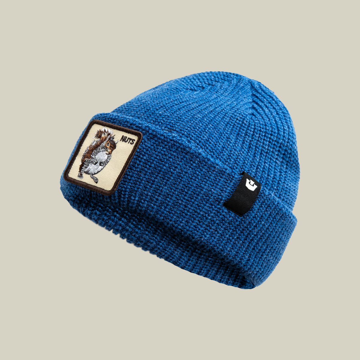 The Nuts Beanie by Goorin Bros is a royal blue ribbed knit beanie featuring a brown squirrel embroidered patch on the front and a small logo patch on the side, displayed against a neutral background.