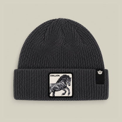 The Stallion Beanie by Goorin Bros is a charcoal gray ribbed knit beanie featuring a black and white stallion patch on the front, displayed flat against a neutral background.