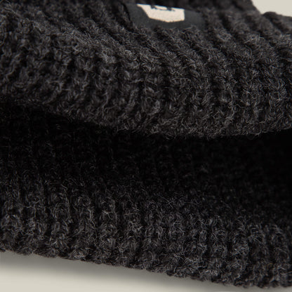 Close-up of black ribbed lightweight poly knit fabric from the Goorin Bros. Air to Fakie, possibly a beanie or sweater, with a small tag partially visible.