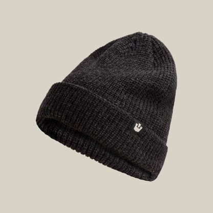 The Goorin Bros. Air to Fakie is a black Watchman beanie with a folded brim and small front logo patch, made from lightweight poly knit for all-season comfort, shown against a plain beige background.