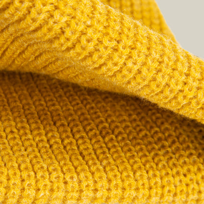 Close-up of folded yellow knitted fabric from the Goorin Bros. Air to Fakie, featuring an all-season ribbed pattern and soft fibers—ideal for a lightweight poly knit Watchman beanie.