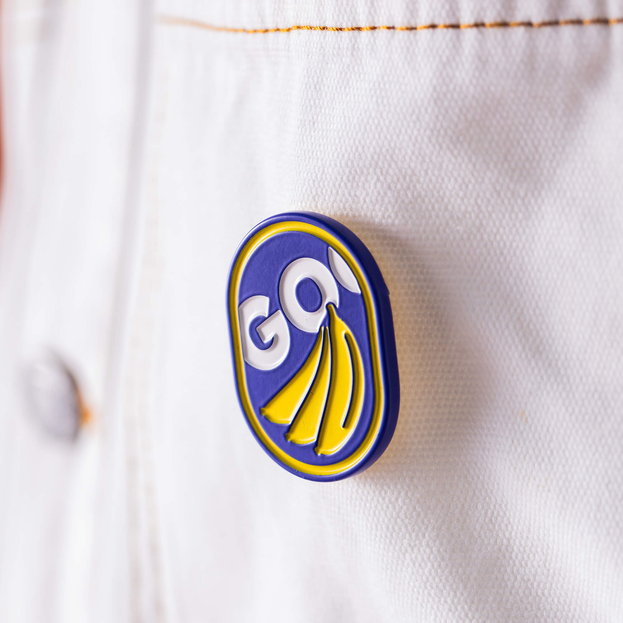 Add a playful touch to your white denim jacket with the GO Bananas Pin by Goorin Bros.—a glossy blue, yellow, and white enamel accessory featuring the word “GO!”.