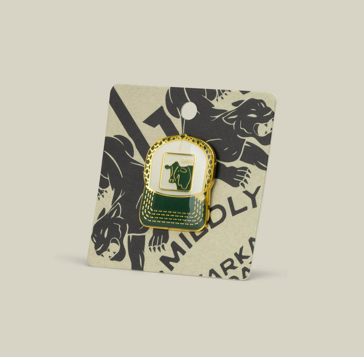 The Cash Cow Trucker Pin by Goorin Bros. is a green and gold enamel zinc alloy pin, attached to a beige card with black puma illustrations.