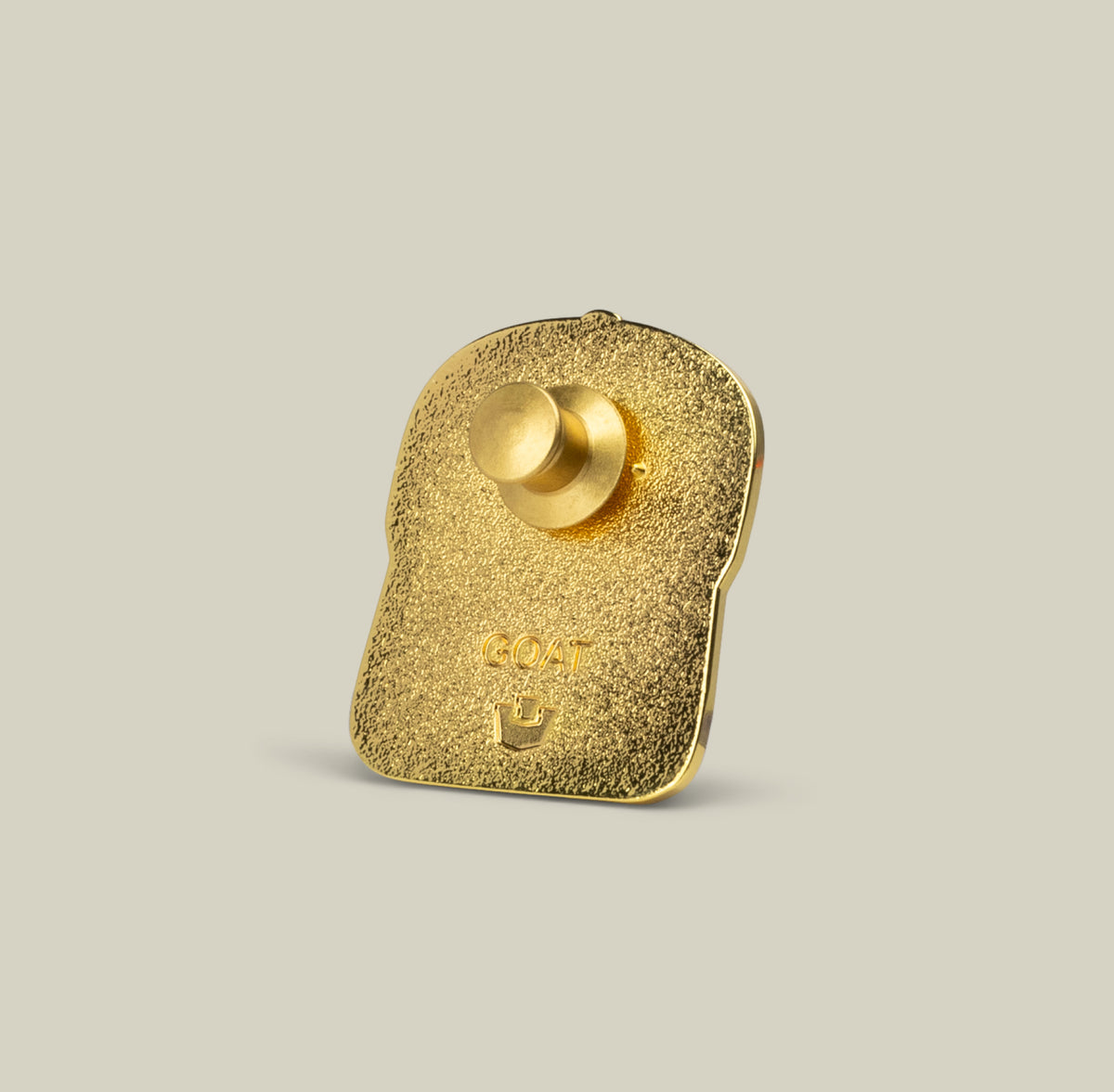 Gold-colored Goat Trucker Pin by Goorin Bros. shown from the back, featuring a textured surface, small crown, copper pin, and butterfly clutch attachment.