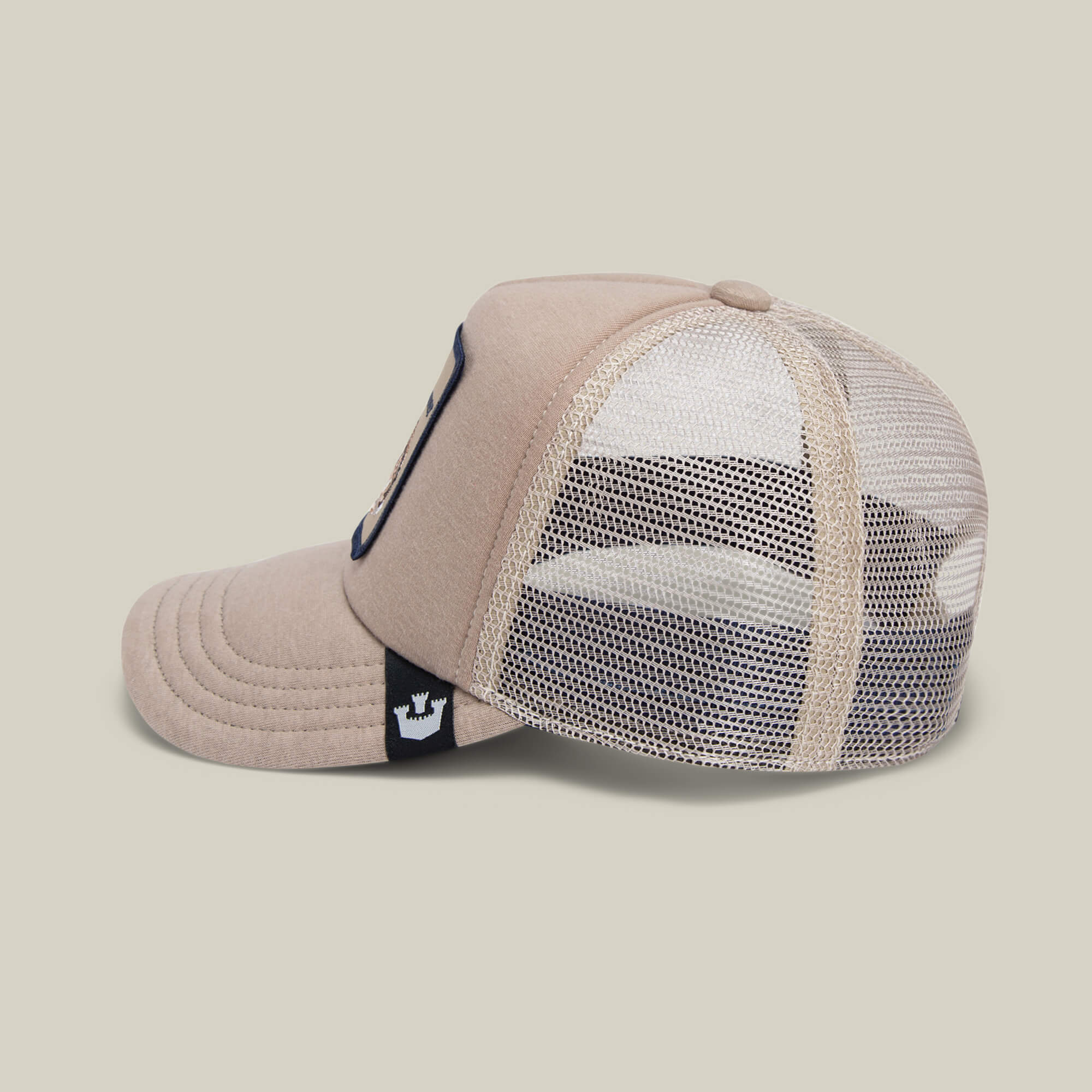 The Goorin Bros. OK Zoomer kids cap features beige mesh and a black-and-white tag with a crown logo, shown in side profile. This stylish hat adds fun flair to any outfit.