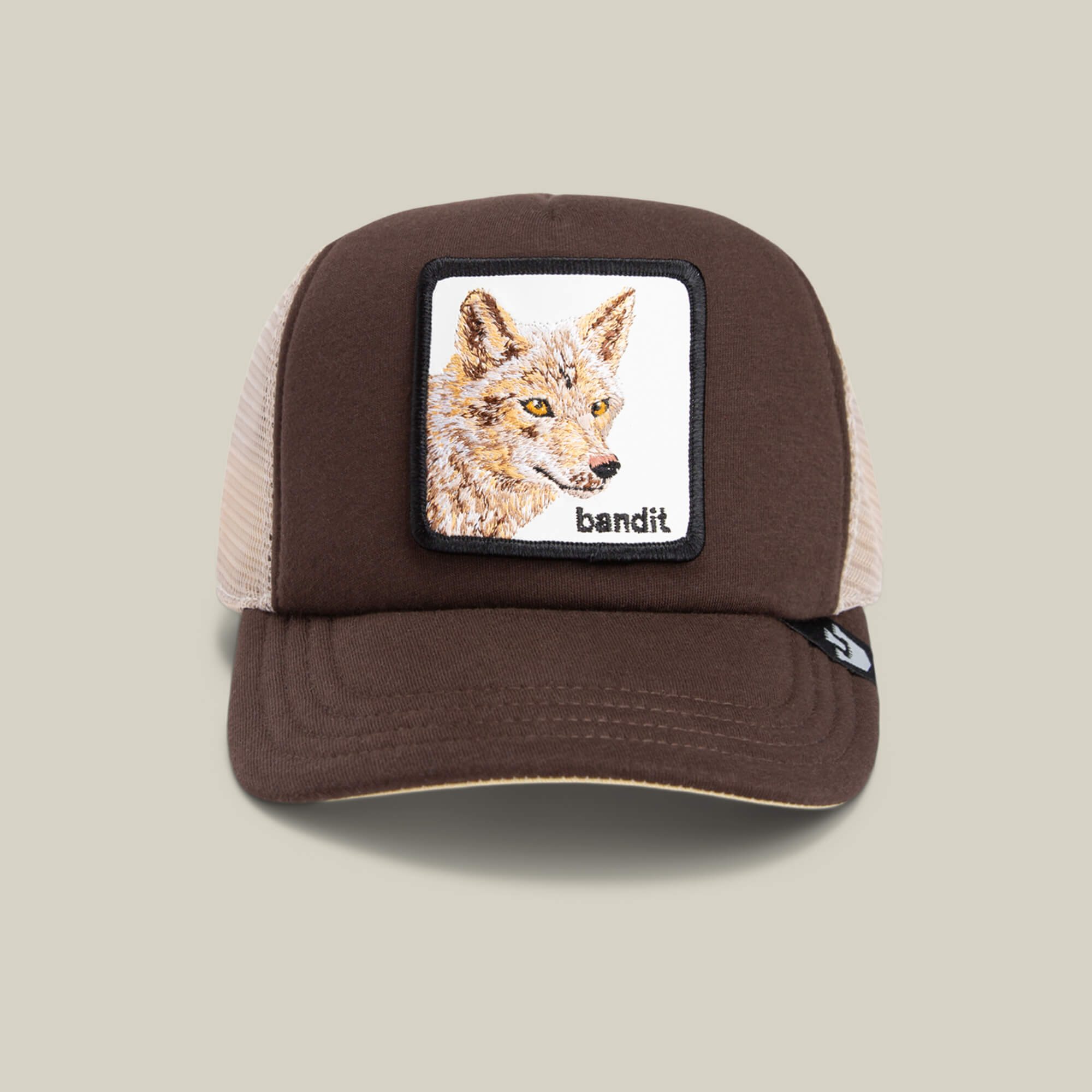 The Chaser by Goorin Bros. is a kids cap in brown and beige, featuring a breathable mesh back, an embroidered coyote patch, and "bandit" on the front.