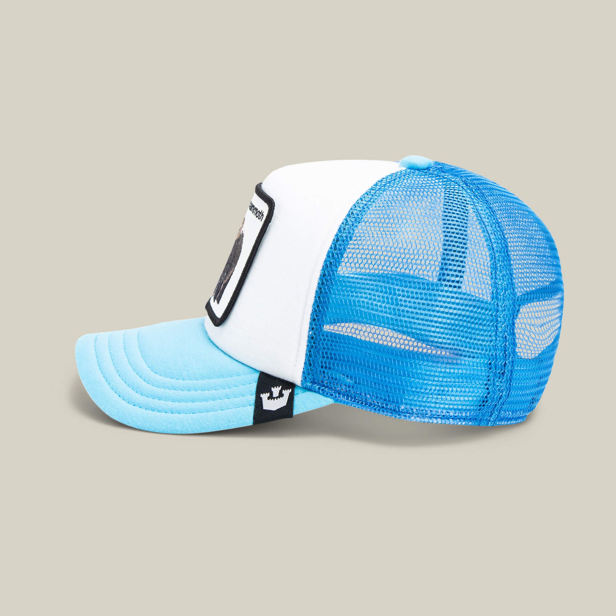 The Mammoth Kiddo by Goorin Bros.—a kids adventure hat featuring a blue and white trucker style, mesh back, light blue curved brim, and embroidered woolly mammoth patch—is shown on a neutral background.